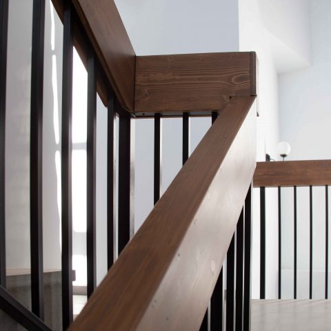 escaleras de hormigón con barandilla de hierro negro y pasamano de madera